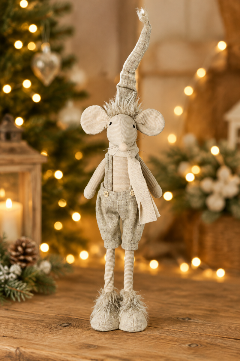 Standing mouse Christmas decoration in dungarees displayed on a wooden surface with warm golden bokeh fairy lights in the background