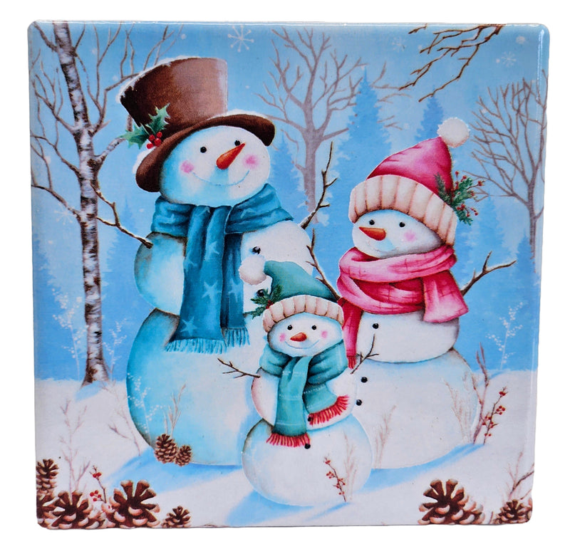 Ceramic Christmas coaster featuring a smiling snowman family in hats and scarves, surrounded by snowy trees, pinecones and berry sprigs.