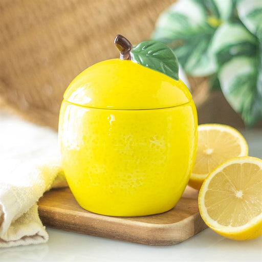 Lemon Ceramic Candle Jar with lid on, styled on a wooden board with fresh lemon slices alongside slices