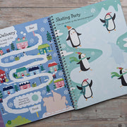 Big Sticker Activity Book Christmas Santa, open spread showing Santa's Delivery trail maze on left and Skating Party penguin matching activity on right, wooden surface