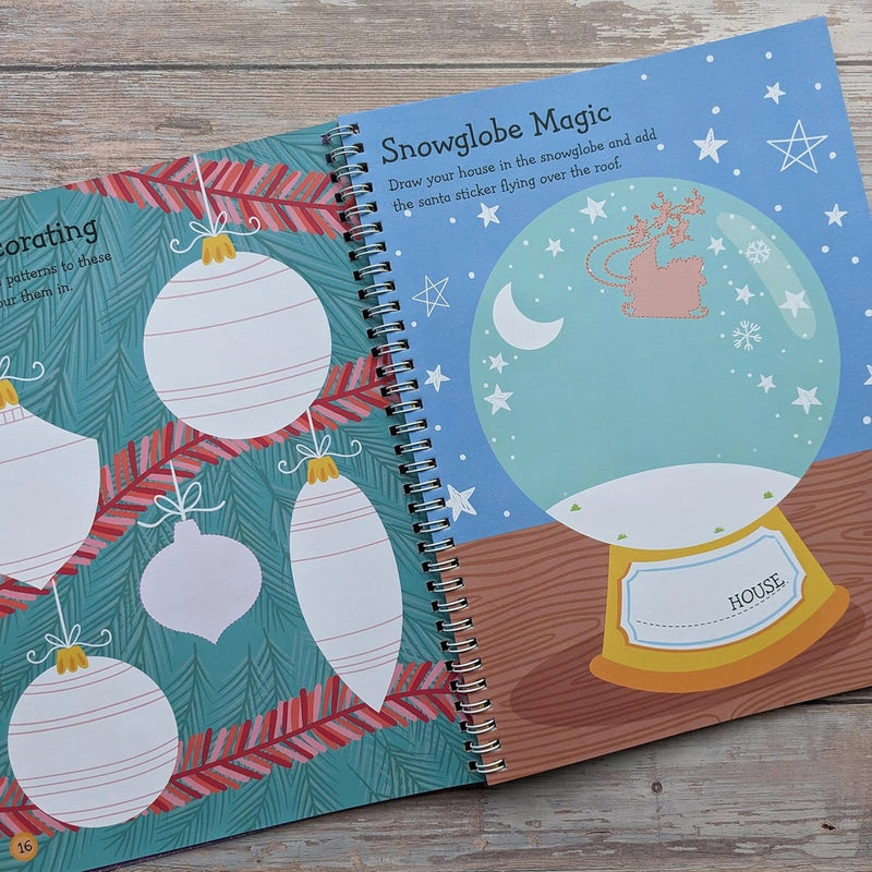Big Sticker Activity Book Christmas Santa, open spread showing bauble decorating activity on left and Snowglobe Magic drawing page on right with Santa's sleigh flying over a snow globe, wooden surface