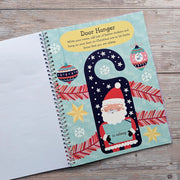 Big Sticker Activity Book Christmas Santa, open spread showing door hanger activity page with illustrated Santa holding an "is asleep" sign, Christmas baubles and snowflakes, wooden surface
