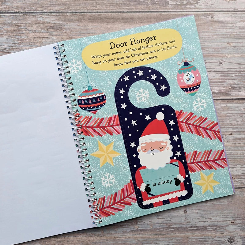Big Sticker Activity Book Christmas Santa, open spread showing door hanger activity page with illustrated Santa holding an "is asleep" sign, Christmas baubles and snowflakes, wooden surface