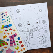 Dress Me Up Snowman Colouring and Activity Book, lifestyle shot showing open book with snowman colouring page and colourful sticker sheet on wooden surface