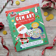 Sparkly Santa Gem Art Activity Book, green and red cover with illustrated Santa holding a gem-decorated bauble, penguin, sleigh and snowflakes, over 1000 gems badge, fold-out scene and card press-outs, lifestyle shot on wooden surface with festive props