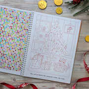 Sparkly Santa Gem Art Activity Book, lifestyle shot showing open spread with gem sticker sheet on left and Christmas tree colouring page with cat and presents on right, wooden surface with gold coins and holly