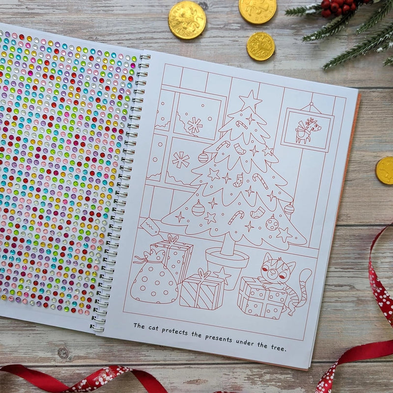 Sparkly Santa Gem Art Activity Book, lifestyle shot showing open spread with gem sticker sheet on left and Christmas tree colouring page with cat and presents on right, wooden surface with gold coins and holly