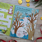 Sparkly Santa Gem Art Activity Book, lifestyle shot showing Mrs Claus maze activity on left and In the Snowy Forest reindeer counting page on right, wooden surface with festive props