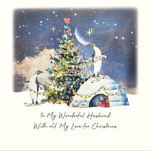 An illustrated Christmas card showing two penguins decorating a glittering Christmas tree topped with a red heart beside an igloo under a starry night sky with a crescent moon, with the sentiment "to My Wonderful Husband with all My Love for Christmas"