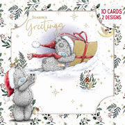 Pack of 10 Tatty Teddy Bear Christmas cards in two designs, showing Tatty Teddy carrying a wrapped present through the snow, framed by festive foliage and stars.”