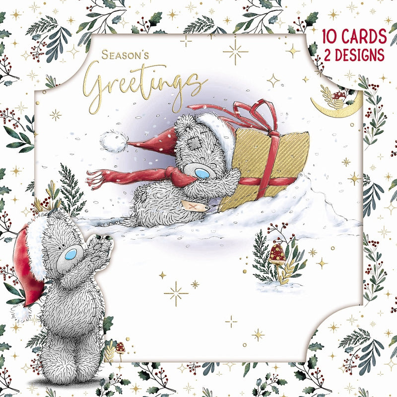 Pack of 10 Tatty Teddy Bear Christmas cards in two designs, showing Tatty Teddy carrying a wrapped present through the snow, framed by festive foliage and stars.”