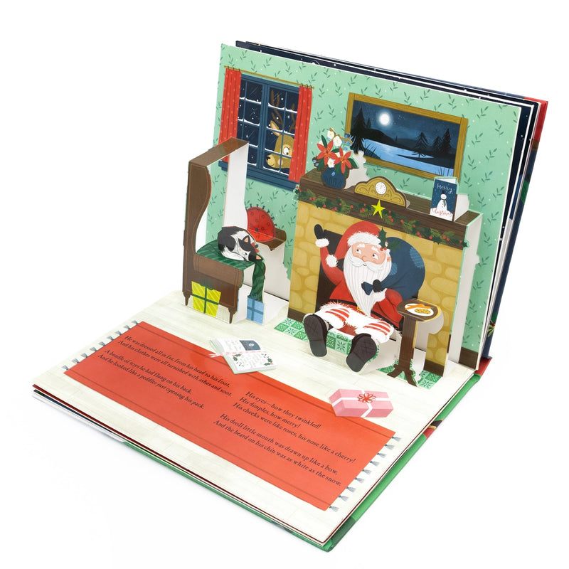 The Night Before Christmas Pop-Up Book full open spread showing Santa seated by a stone fireplace pop-up with a sleeping cat in an armchair, on a white background