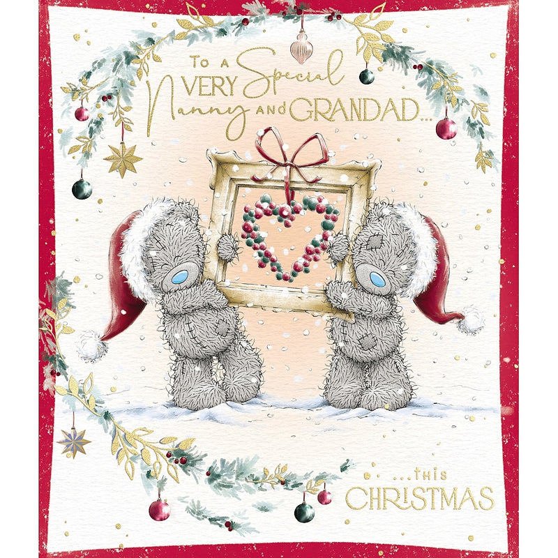 Very Special Nanny and Grandad Tatty Teddy Christmas card featuring two bears wearing Santa hats and holding a framed bauble heart topped with a bow, surrounded by festive foliage and hanging decorations