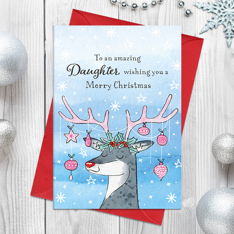 Amazing Daughter Christmas card featuring a smiling illustrated reindeer with holly and berries on its head, baubles and a star hanging from its antlers, surrounded by snowflakes and stars