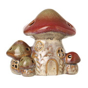 Toadstool tea light holder with large mushroom house, solid arched doorway, two windows, cut-out holes in the domed cap and smaller toadstools at the side, unlit, 12 x 8.5 x 10.8cm