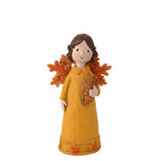 Country Living autumn fairy figurine small, mustard yellow dress with leaf-print hem, warm orange-toned leaf wings, holding autumnal foliage, front view on white background