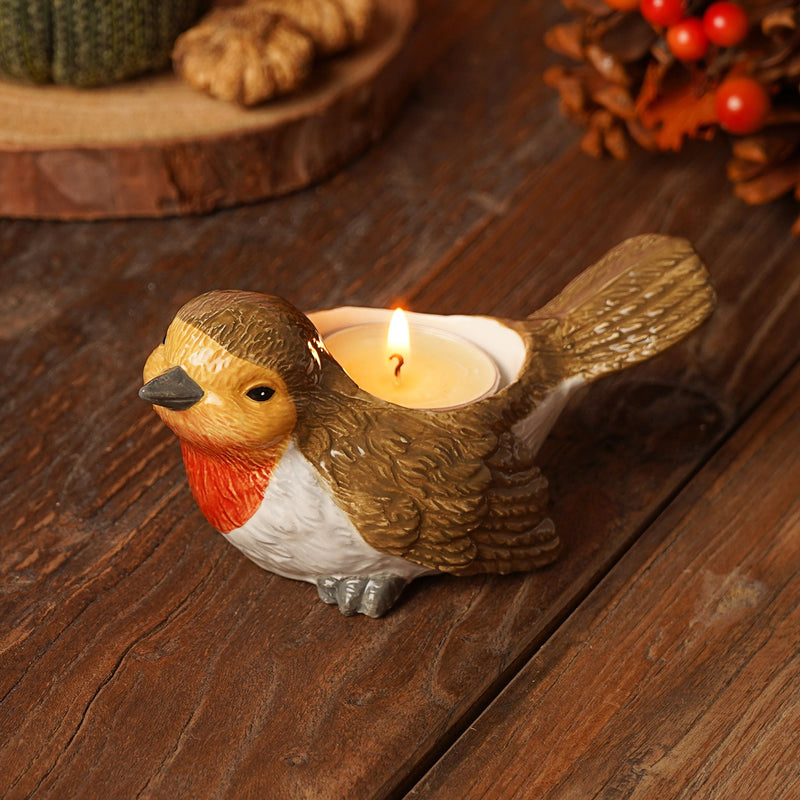 Country Living robin tea light holder, plump robin figurine with rich red breast and brown feathered body, lit tea light in back, autumn lifestyle shot on wooden surface