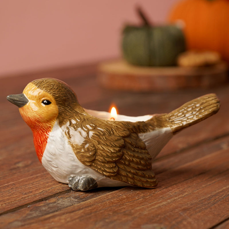 Country Living robin tea light holder, lifestyle shot with lit tea light on wooden surface, autumn pumpkin display in background