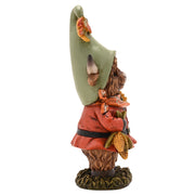 Highland cow autumn figurine, side view showing sage green pointed hat, terracotta coat with black belt, corn cobs detail, white background