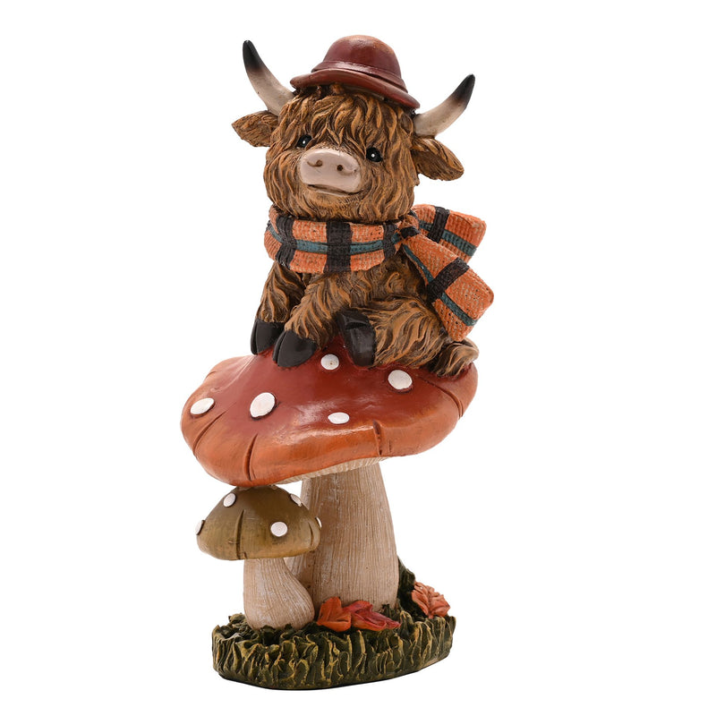 Highland cow on mushroom figurine, front view showing bowler hat, orange tartan scarf and expressive face, rust-coloured toadstool with white spots, white background