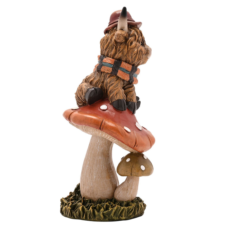 Highland cow on mushroom figurine, side view showing shaggy fur detail and tartan scarf, rust-coloured toadstool, white background