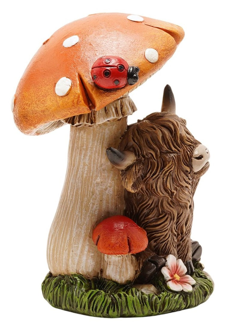 Highland Cow Toadstool Figurine side view showing highland cow with curved horns leaning against toadstool stem with ladybird, wildflowers at base, on white background