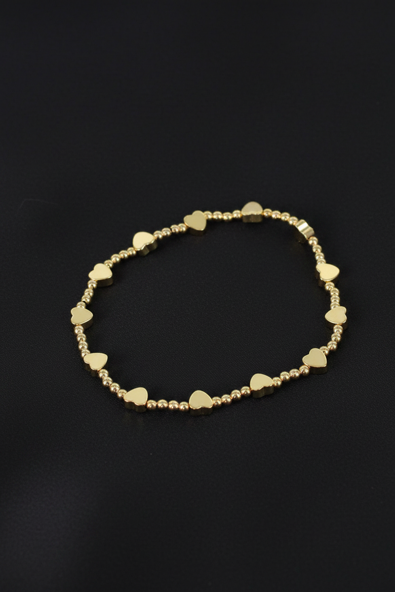 18ct gold plated elasticated bracelet with alternating round beads and flat heart beads on a black background