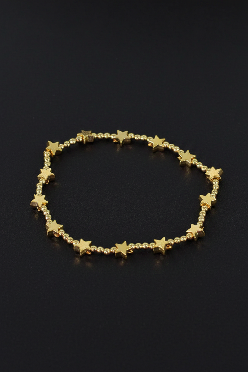 18ct gold plated elasticated bracelet with alternating round beads and flat star beads on a black background