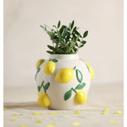  Hestia white ceramic vase with lemon design 12cm, styled with green leaves inside and lemon petals scattered around the base