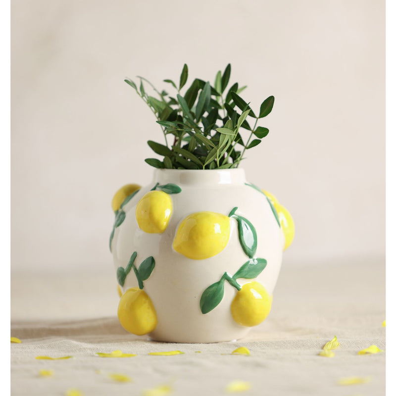  Hestia white ceramic vase with lemon design 12cm, styled with green leaves inside and lemon petals scattered around the base