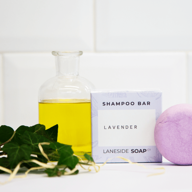 Laneside Soap Co Lavender Shampoo Bar and gift box styled on a white bathroom shelf with a glass bottle of oil and trailing green ivy
