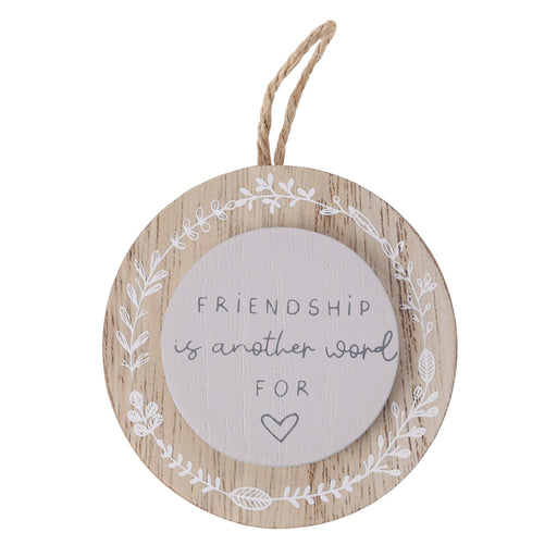 Moments circular wooden hanging plaque with jute loop and white leaf wreath border, sentiment reads Friendship is another word for love with heart detail, white background