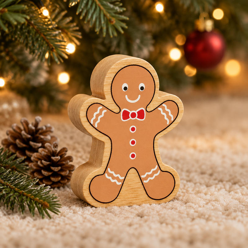 Wooden gingerbread man toy beneath Christmas tree branches beside small pinecones and warm fairy lights