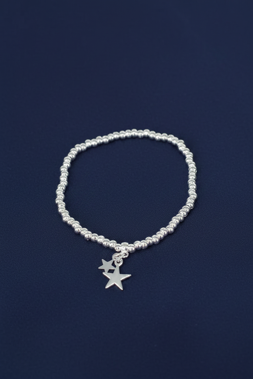 Silver plated elasticated bracelet with two dangling silver star charms on a ball bead band, on a deep navy blue background
