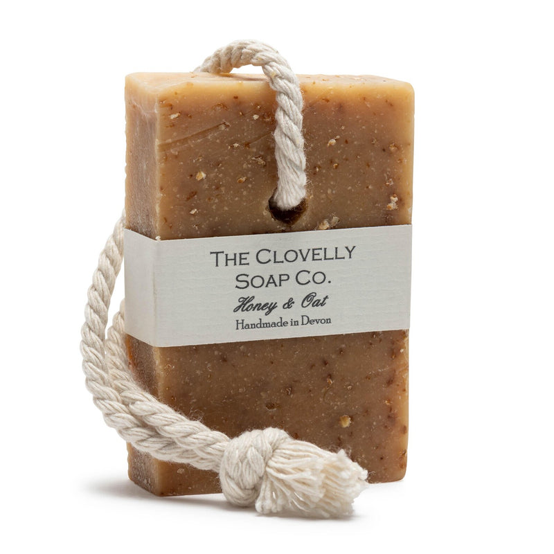 Clovelly Soap Co. Honey & Oat handmade bar soap on an unbleached cotton rope, golden-brown oat-speckled cold-process bar with white paper label, handcrafted in Devon