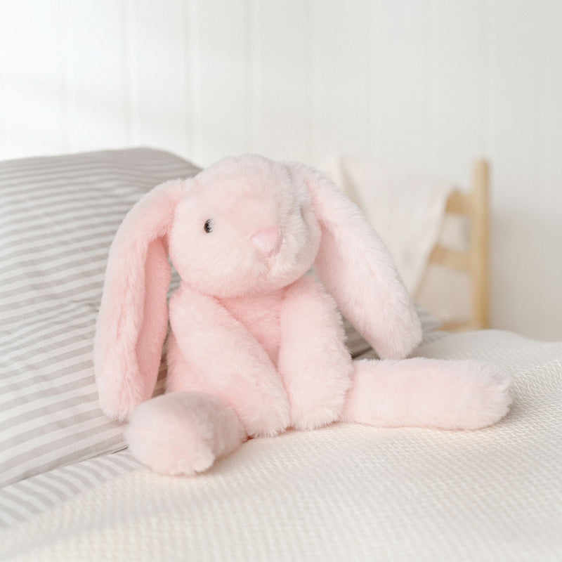 Katie the plush long leg light pink bunny soft toy 35cm, lifestyle shot — sitting on a bed
