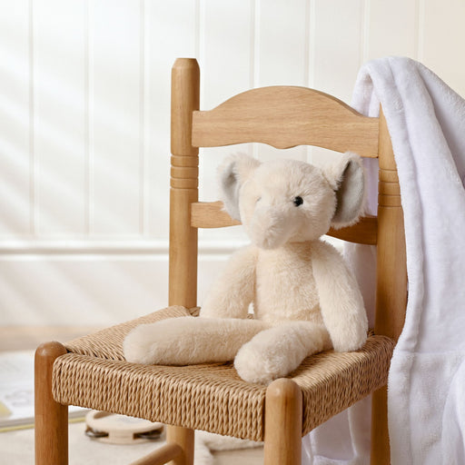 Ellie the Elephant plush long leg soft toy sitting on a wooden chair in a bright nursery setting