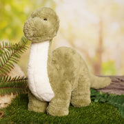 Dan the plush Diplodocus soft toy 36cm, lifestyle shot — styled in a forest setting