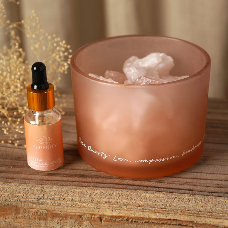Serenity Rose Quartz crystal bowl diffuser with rose quartz crystals and Flow fragrance oil bottle on wooden surface with dried flowers