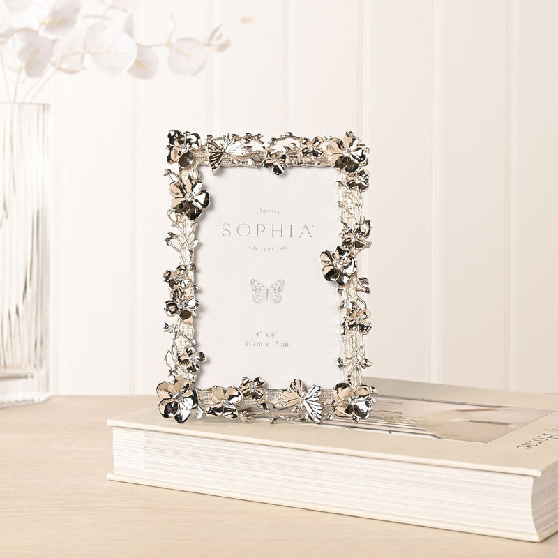 Sophia floral butterfly nickel-plated photo frame lifestyle shot standing on book on wooden surface with white flowers in background