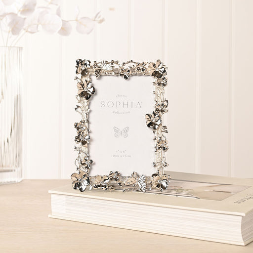 Sophia floral butterfly nickel-plated photo frame lifestyle shot standing on book on wooden surface with white flowers in background