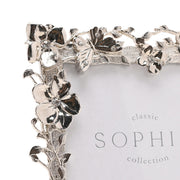 Close-up of Sophia floral butterfly nickel-plated photo frame corner showing flower, leaf and butterfly detail with crystal-effect stone centres, white background