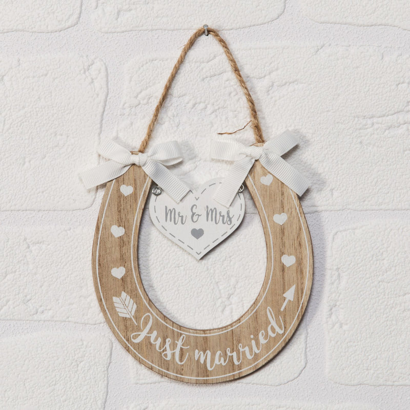 Just Married Wooden Horseshoe Hanging Plaque displayed on white brick wall showing natural wood finish with Just Married script and Mr and Mrs heart tag