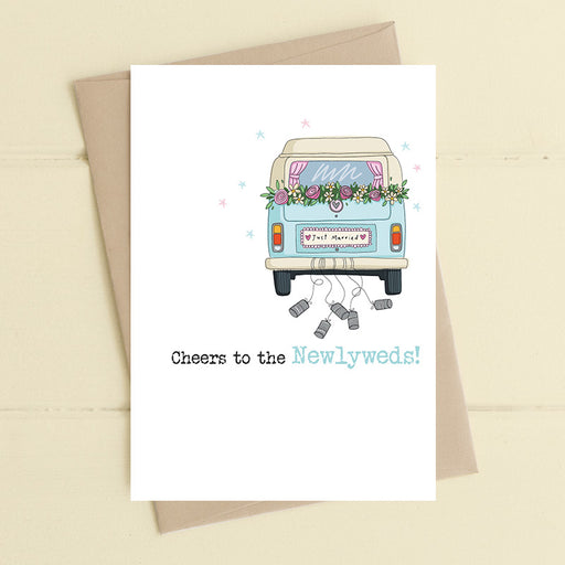 Wedding card featuring an illustrated vintage campervan decorated with a floral garland just above the rear window and a Just Married numberplate with tin cans trailing behind and the sentiment Cheers to the Newlyweds