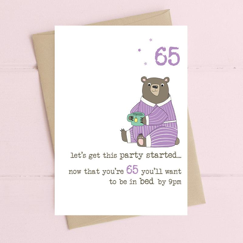 Funny 65th birthday card with a bear in stripy purple pyjamas holding a mug, with the message "let's get this party started… now that you're 65 you'll want to be in bed by 9pm"