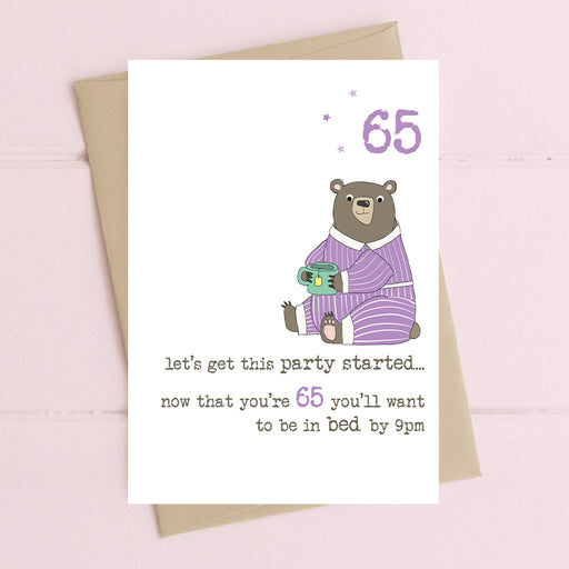 Funny 65th birthday card with a bear in stripy purple pyjamas holding a mug, with the message "let's get this party started… now that you're 65 you'll want to be in bed by 9pm"